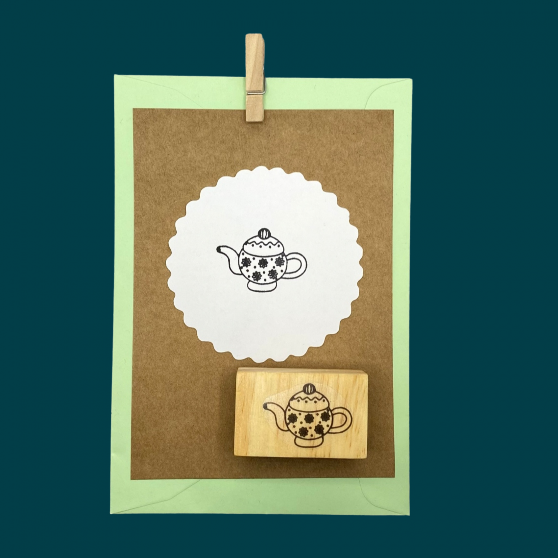 Carimbo de madeira com desenho de bule e cartões coloridos presos por pregador de madeira