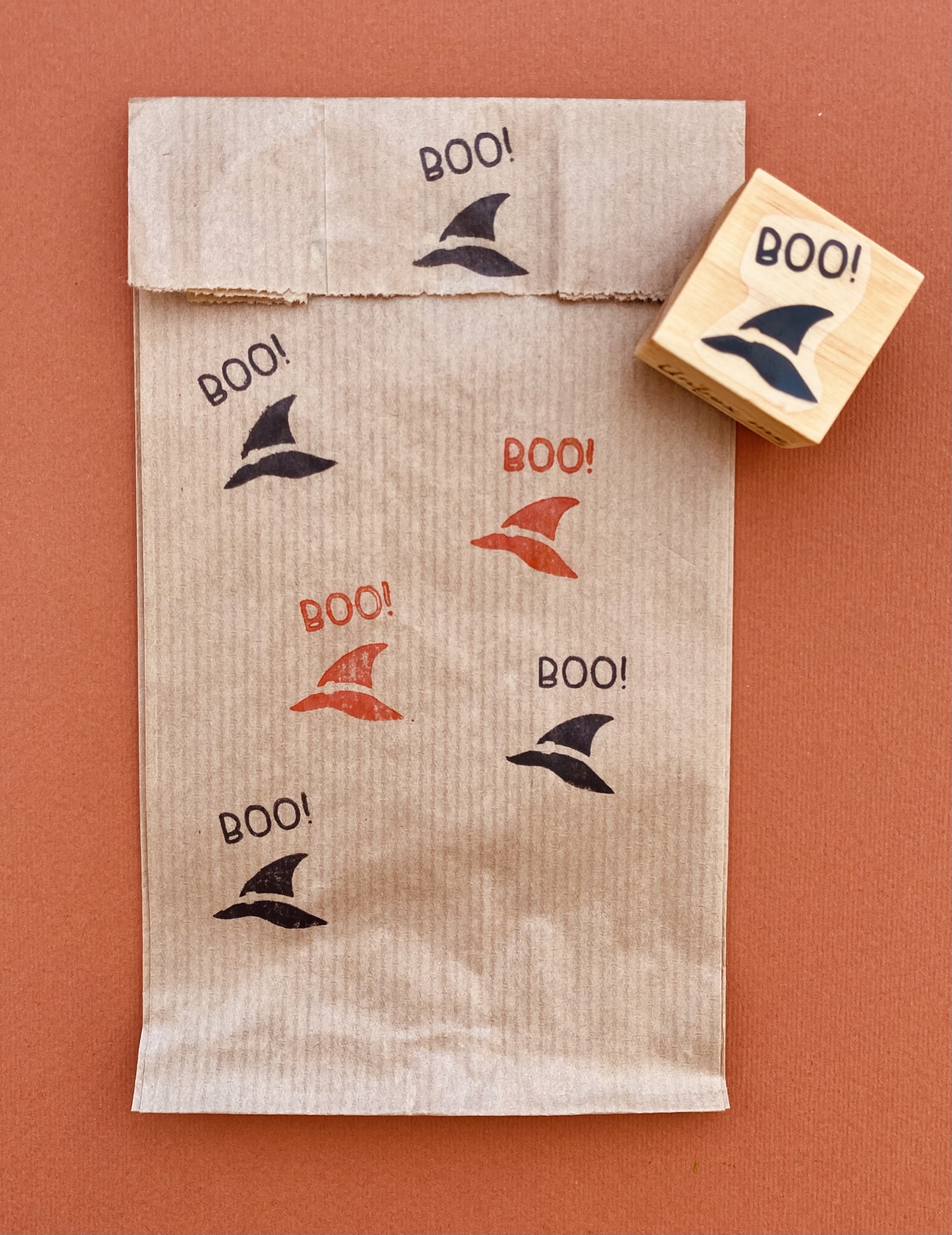 Saco de papel castanho com estampas de chapéu de bruxa e palavra BOO