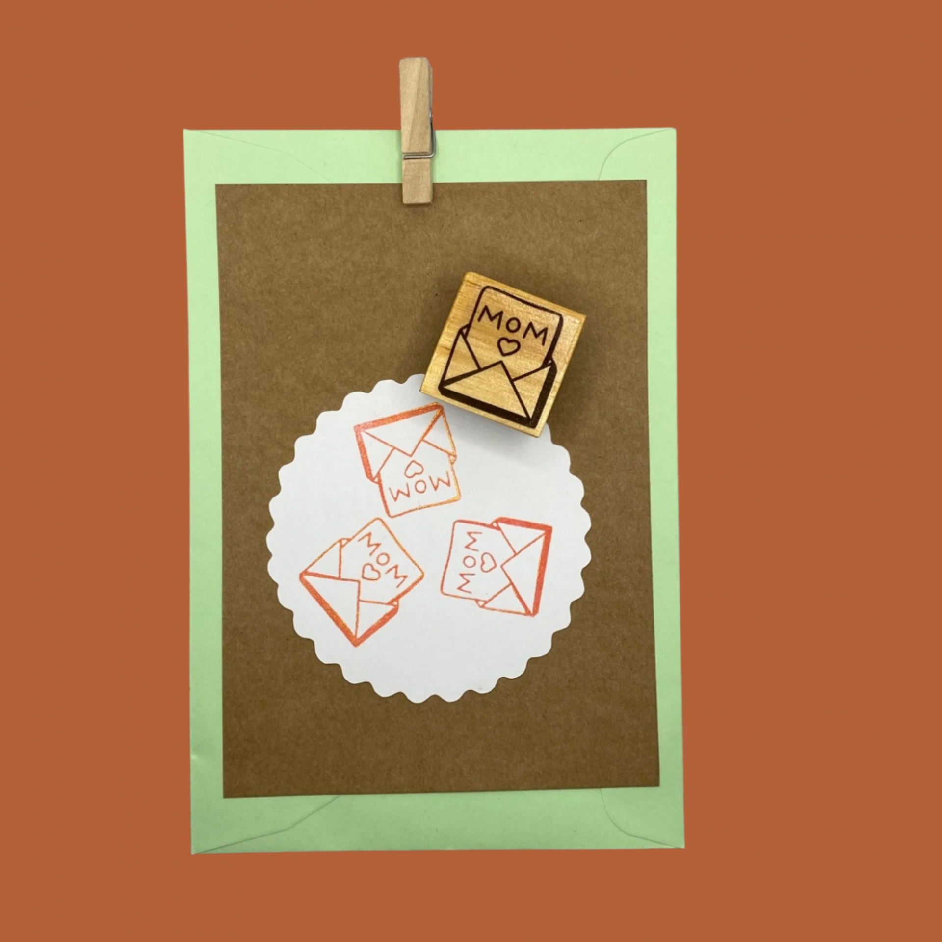 Carimbo de madeira com desenho de envelope e texto MOM com coração