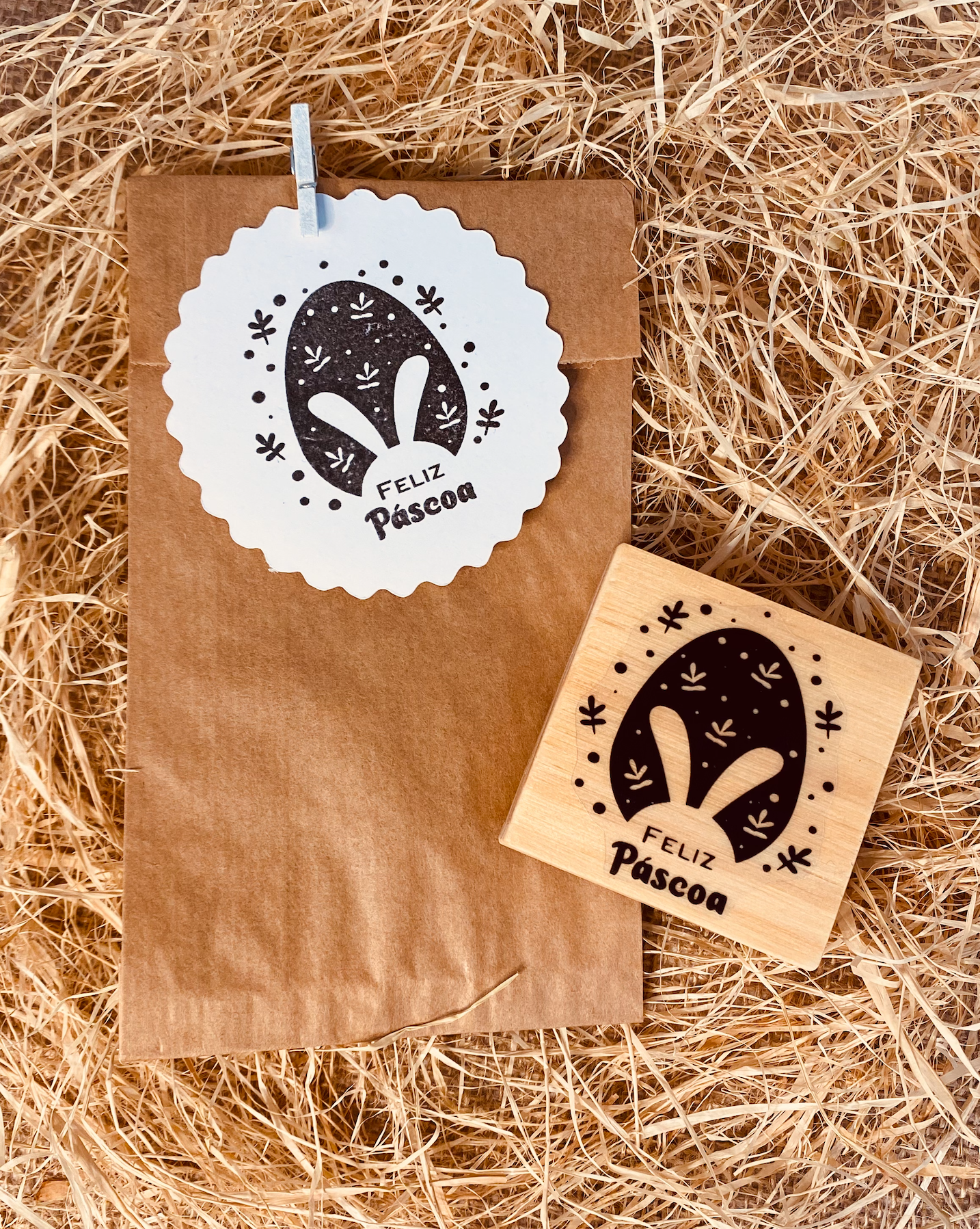 Selo de carimbo e pacote de papel com etiqueta FELIZ Páscoa sobre palha