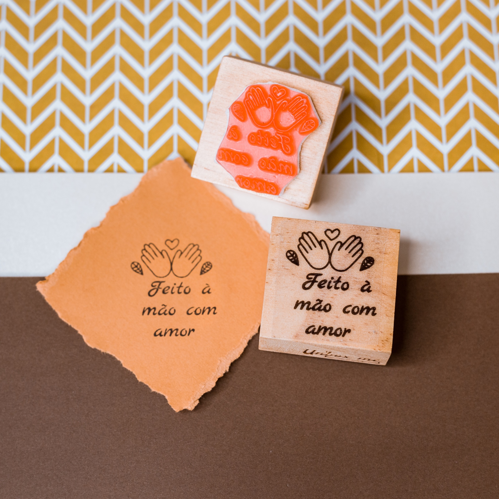 Carimbo de madeira com texto e símbolo de mãos sobre papel e fundo geométrico