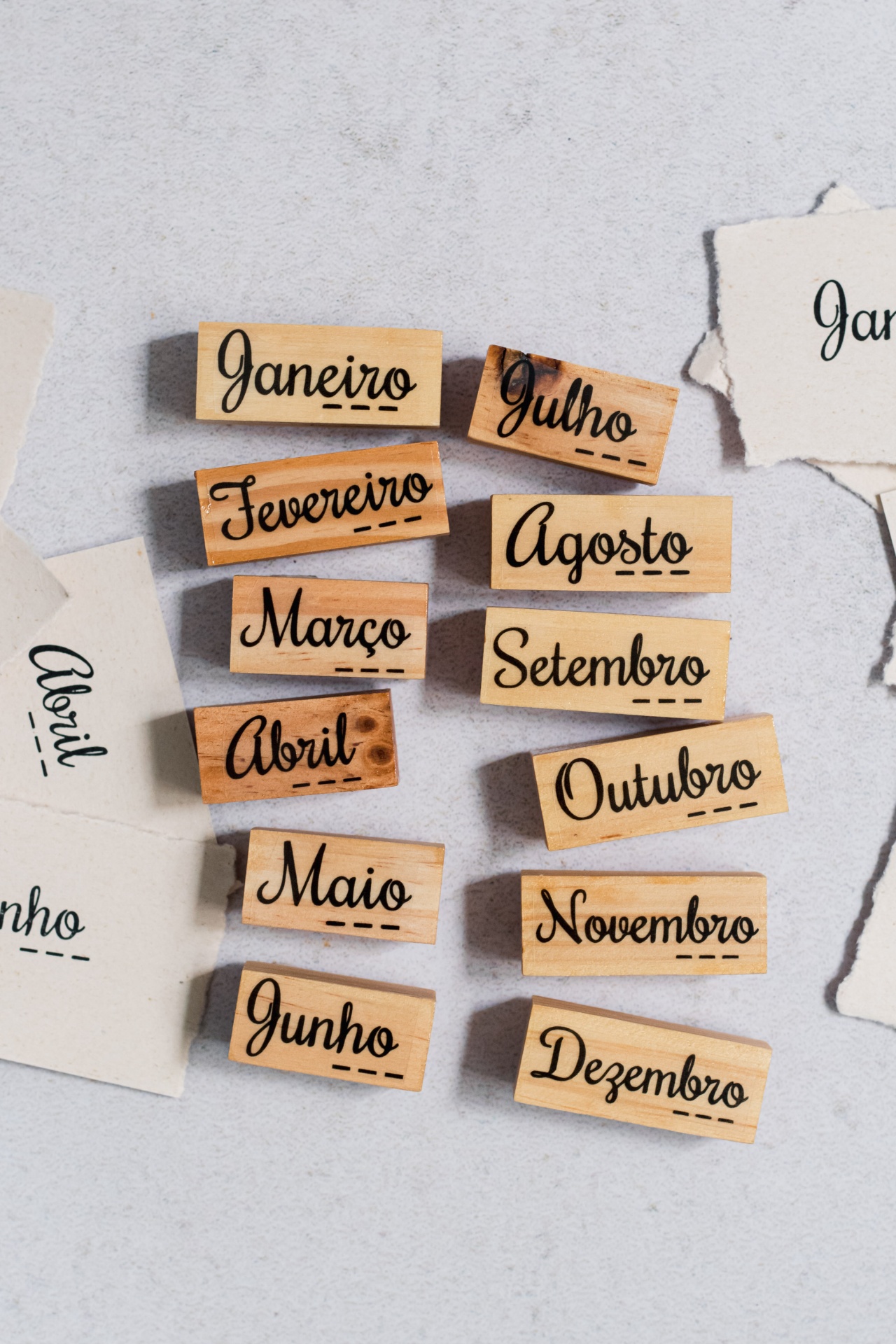 Blocos de madeira com nomes dos meses do ano em português em letras pretas cursivas