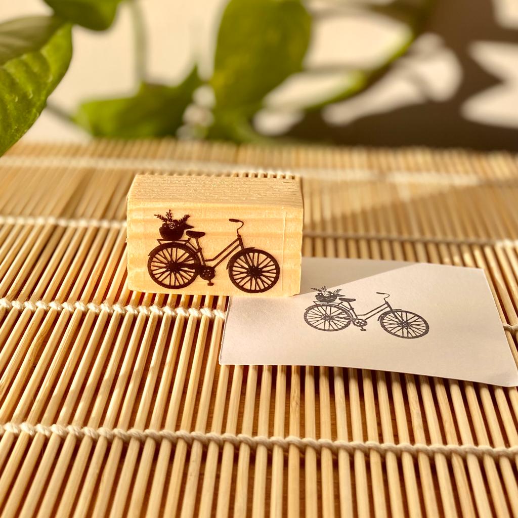 Carimbo de madeira com desenho de bicicleta e papel com impressão do desenho