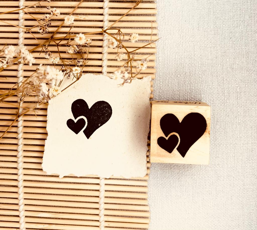 Selo de madeira com corações pretos e papel com a mesma estampa ao lado