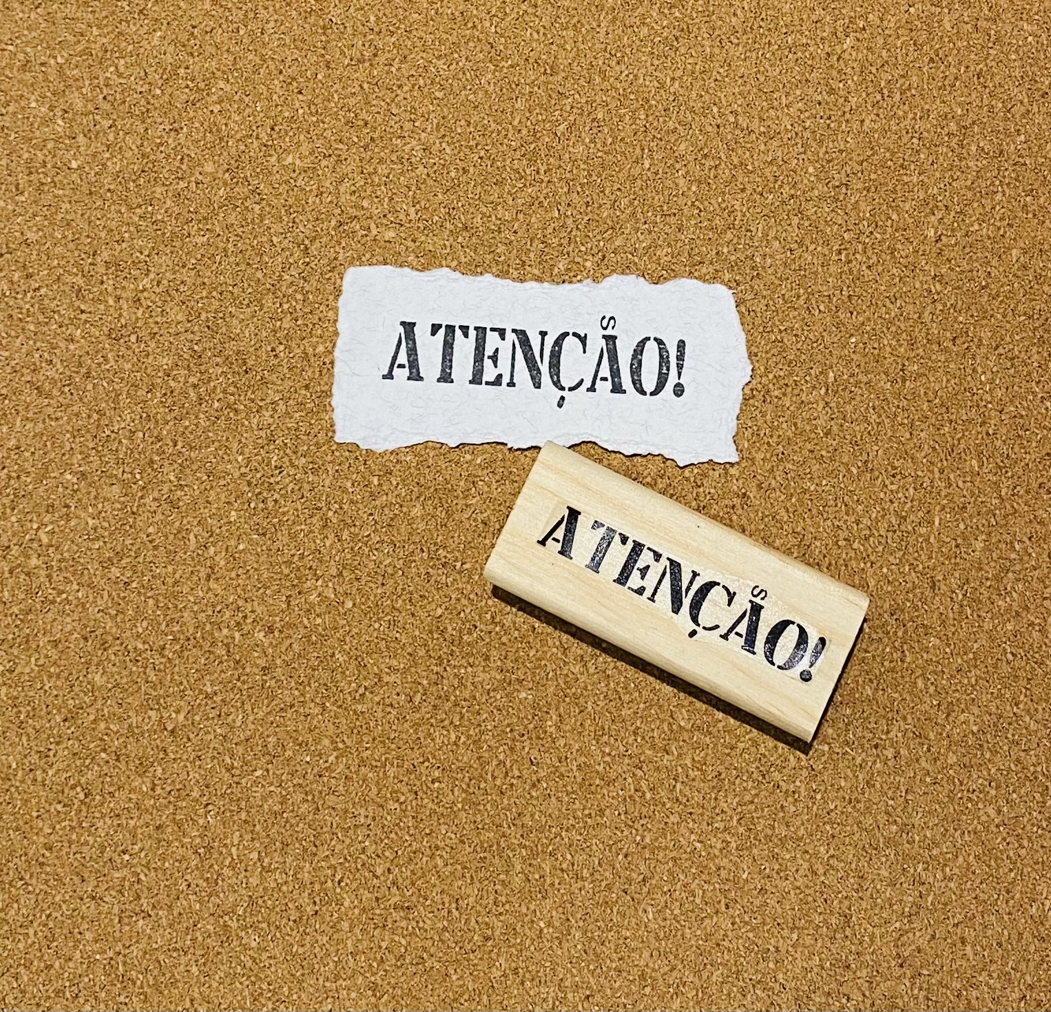Carimbo de madeira com a palavra 'ATENÇÃO!' e papel com a mesma palavra carimbada