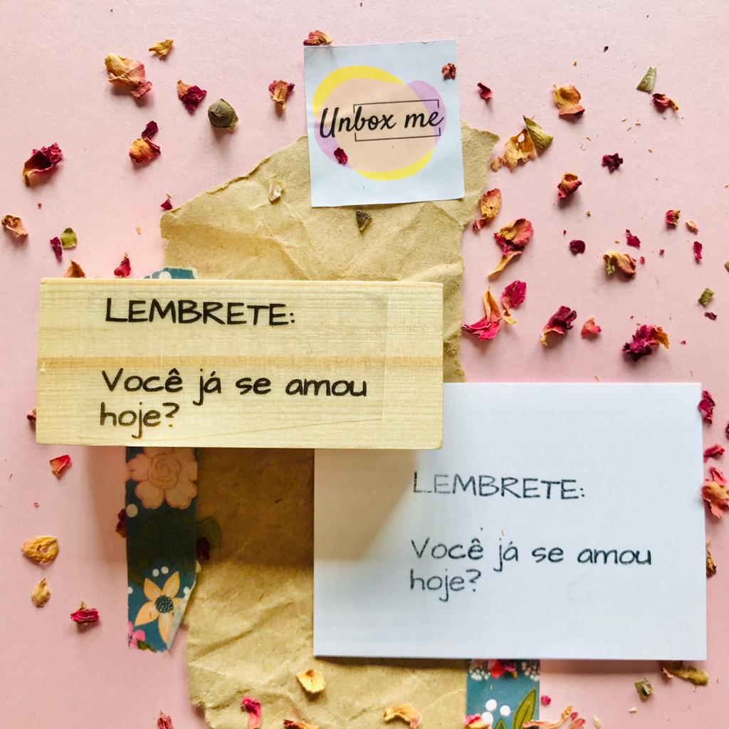 Notas com lembrete em madeira e papel, fundo rosa com pétalas secas e papel kraft