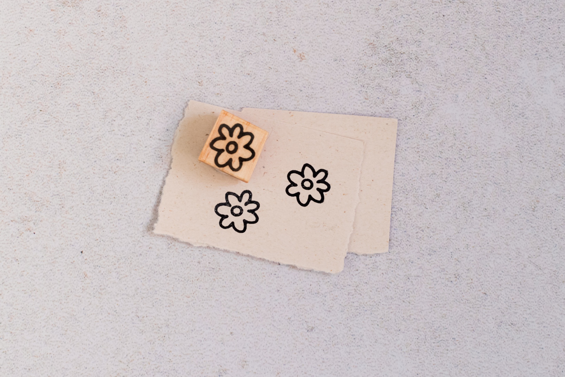 Carimbo de madeira com padrão de flor preta sobre papel bege