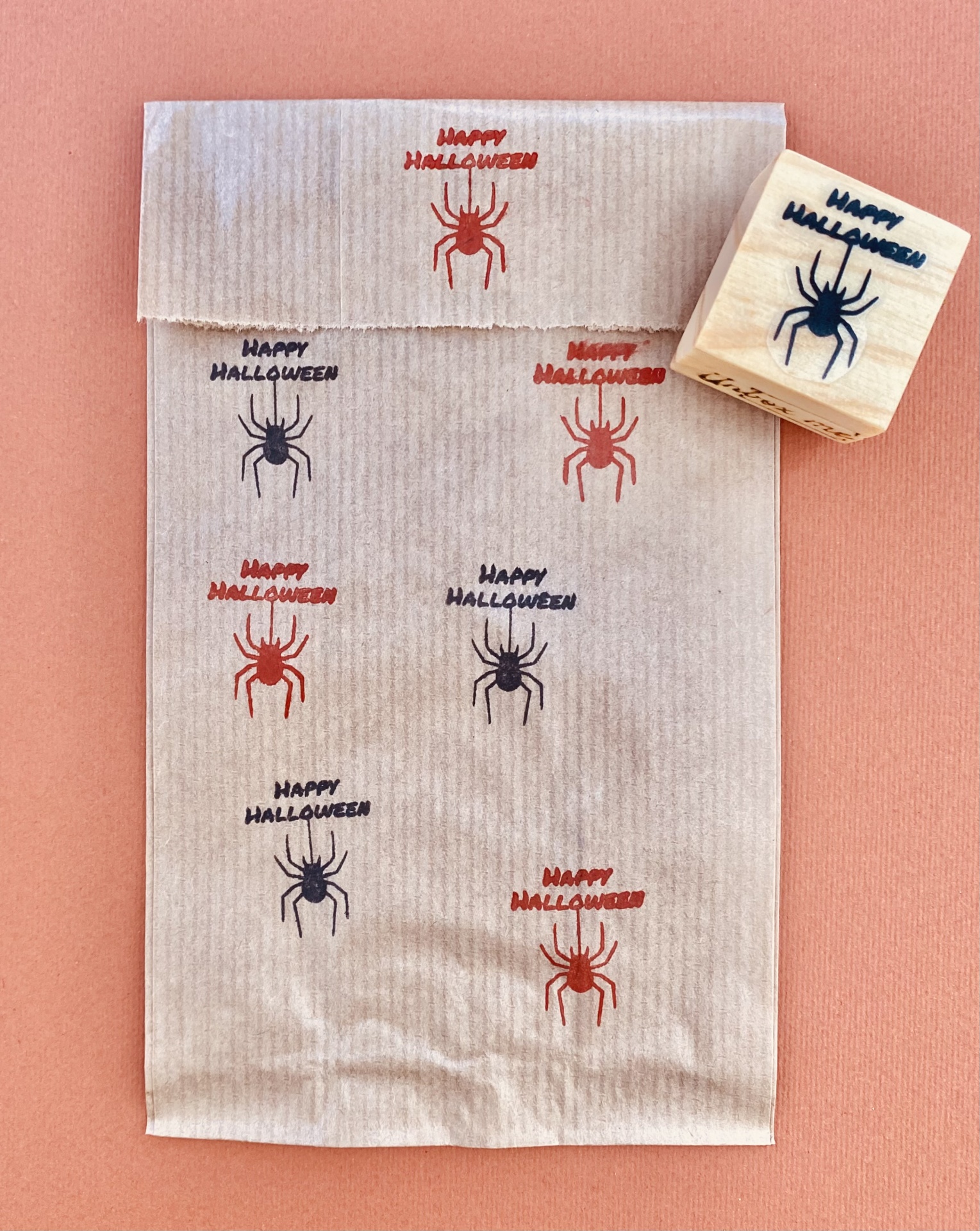 Saco de papel castanho com carimbos de aranha e texto 