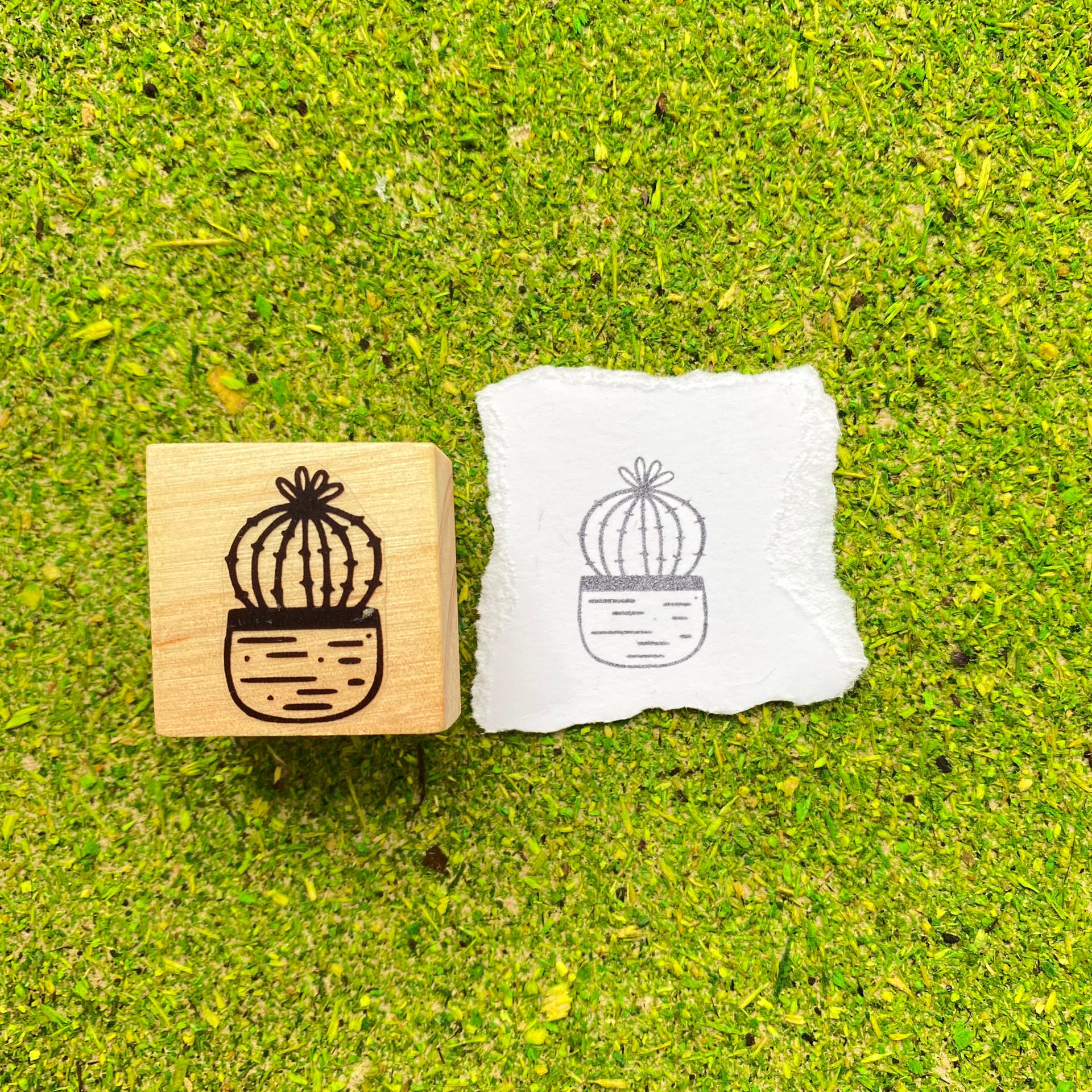 Carimbo de madeira com desenho de cacto e impressão em papel sobre fundo verde texturizado
