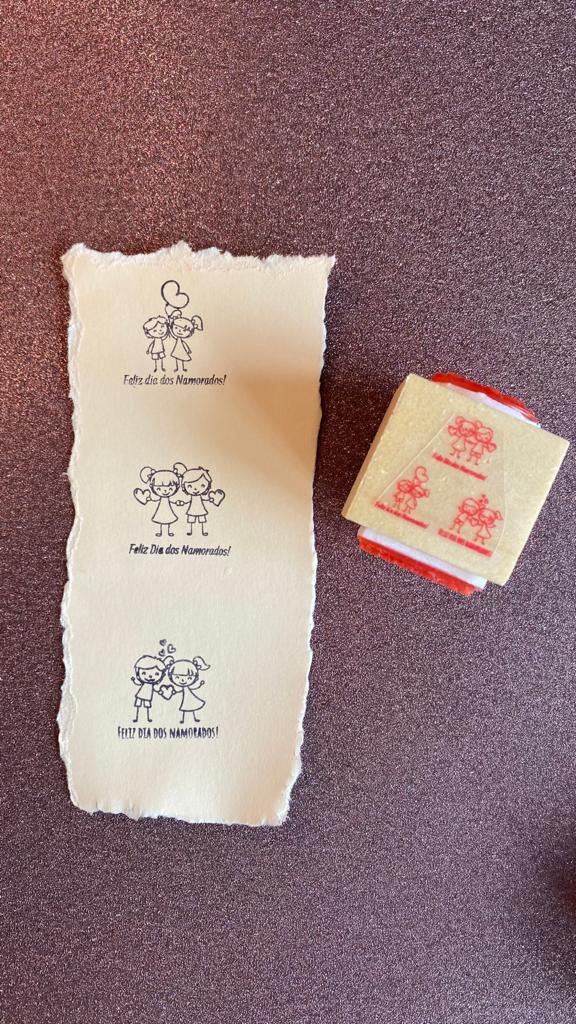 Carimbo de madeira e papel com desenhos de casais e texto Feliz dia dos Namorados