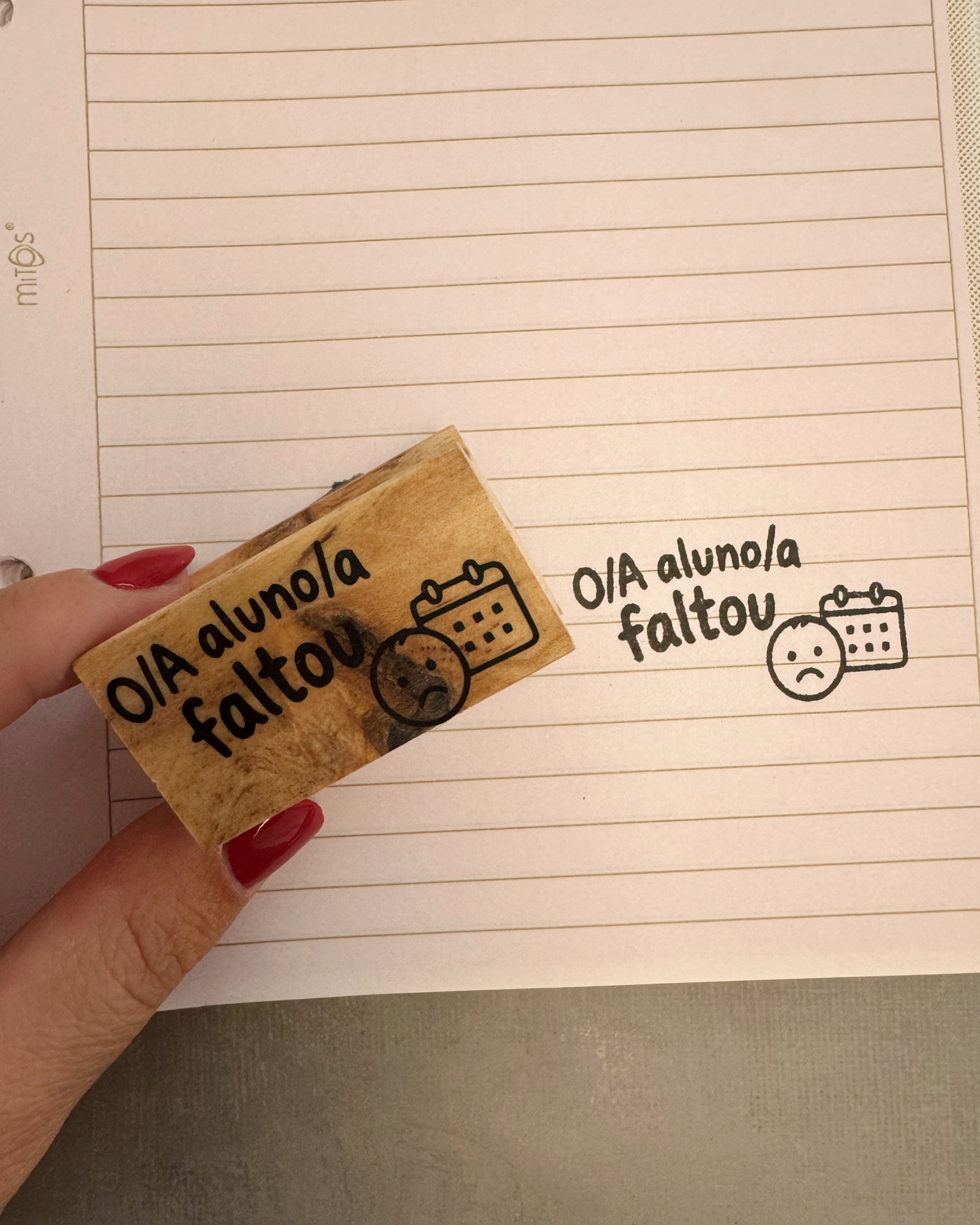 Carimbo de madeira com texto e desenhos em cima de papel com linhas