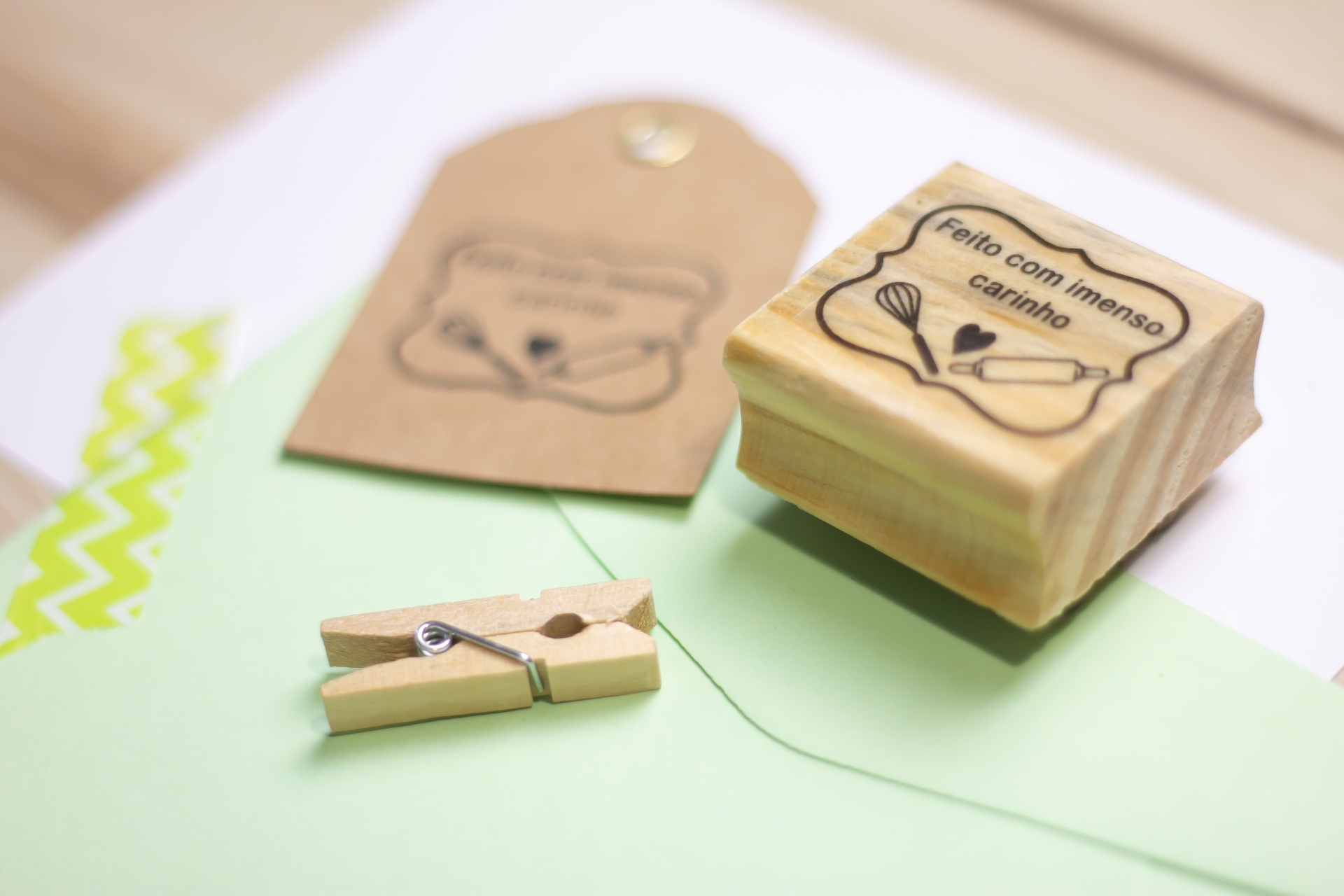 Carimbo de madeira com inscrição FELIZ COM IMENSO CARINHO e etiqueta em cartão reciclado com o mesmo desenho, pregador de madeira e envelope verde claro