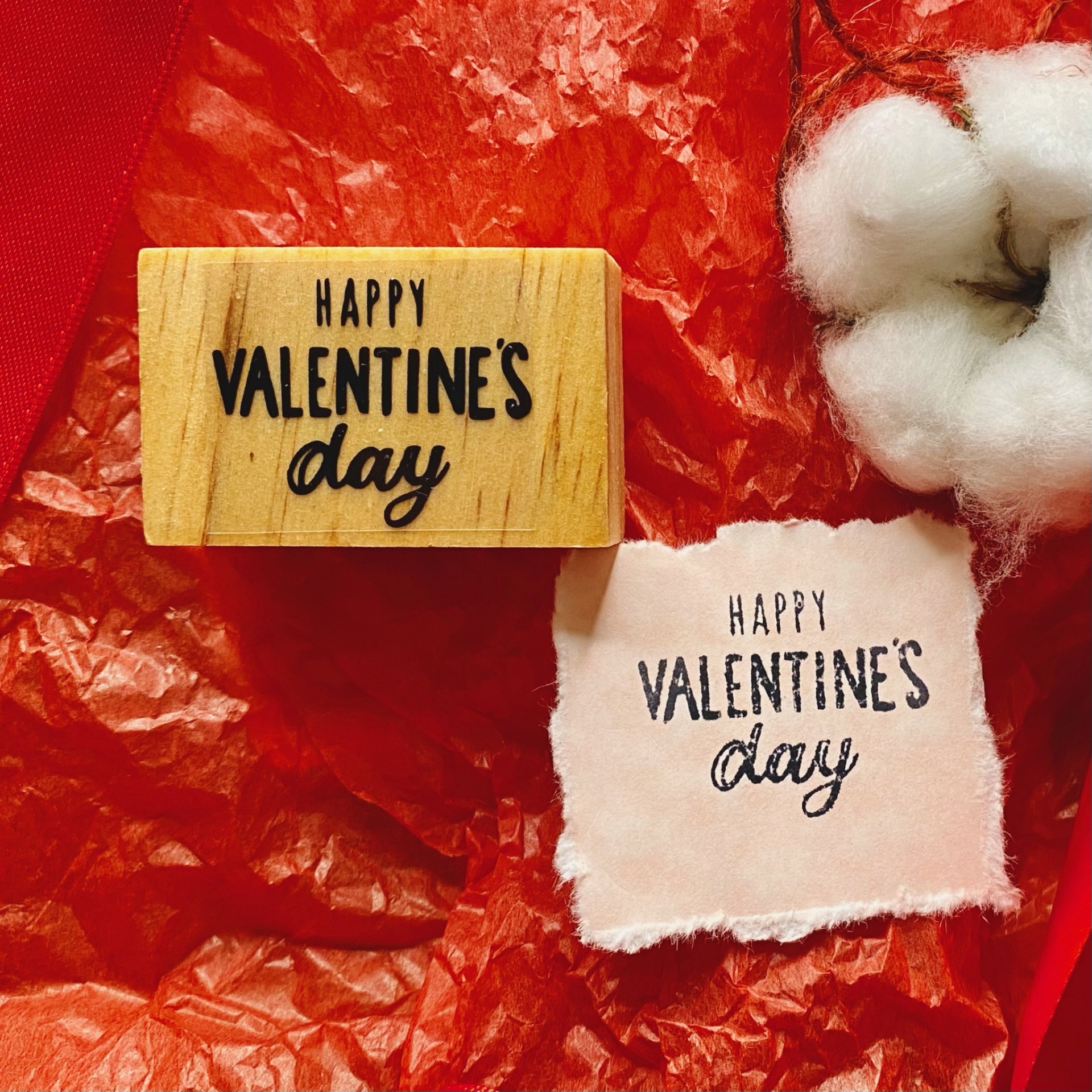 Carimbo de madeira com texto Valentine's Day, impressão em tecido e algodão sobre papel vermelho.