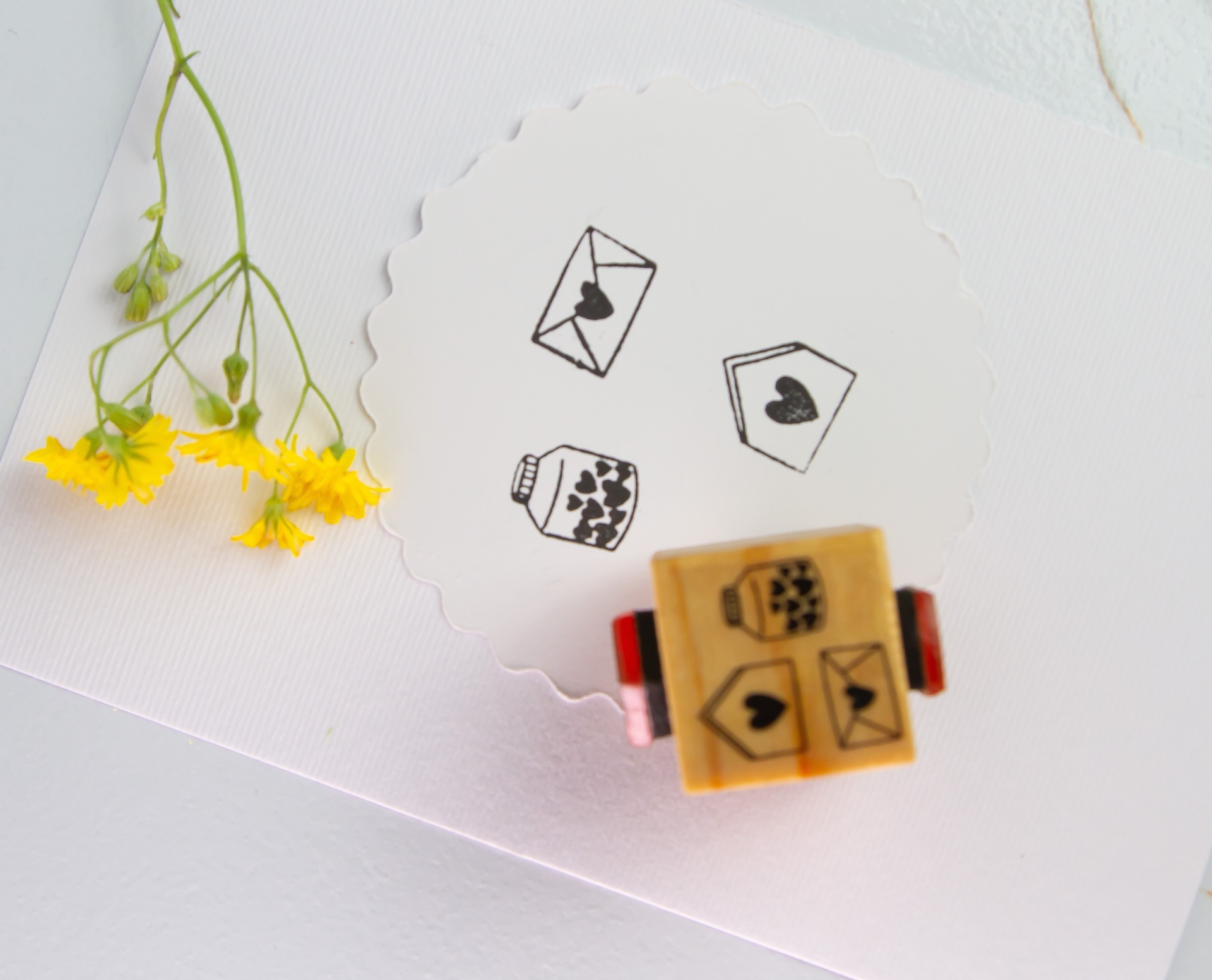 Selo de borracha com desenhos de carimbos, papel branco e flores amarelas