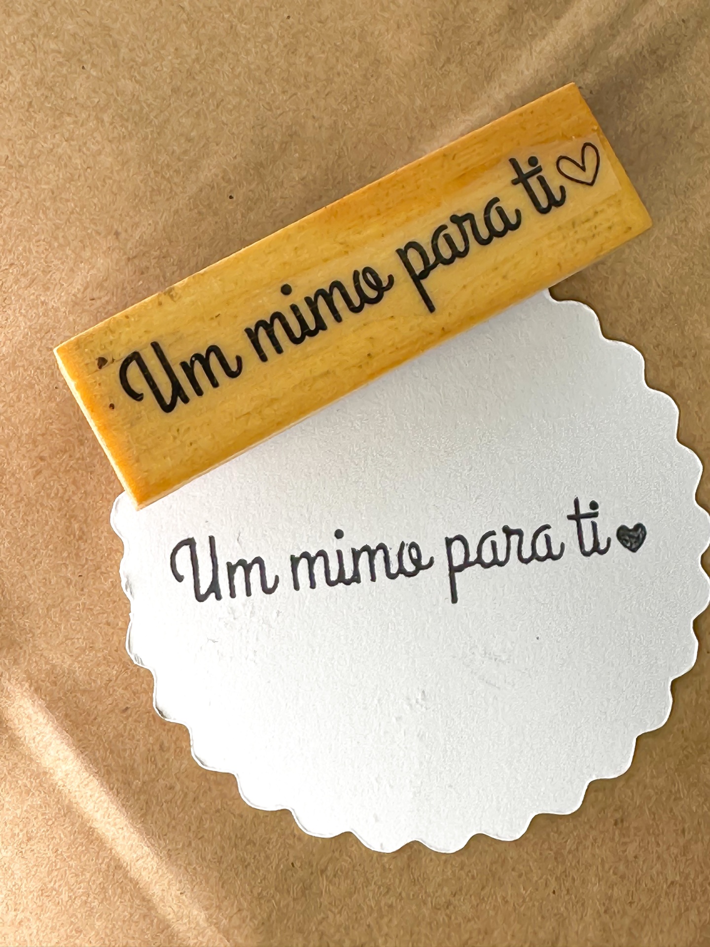 Carimbo de madeira com texto 'Um mimo para ti' e papel carimbado com o mesmo texto