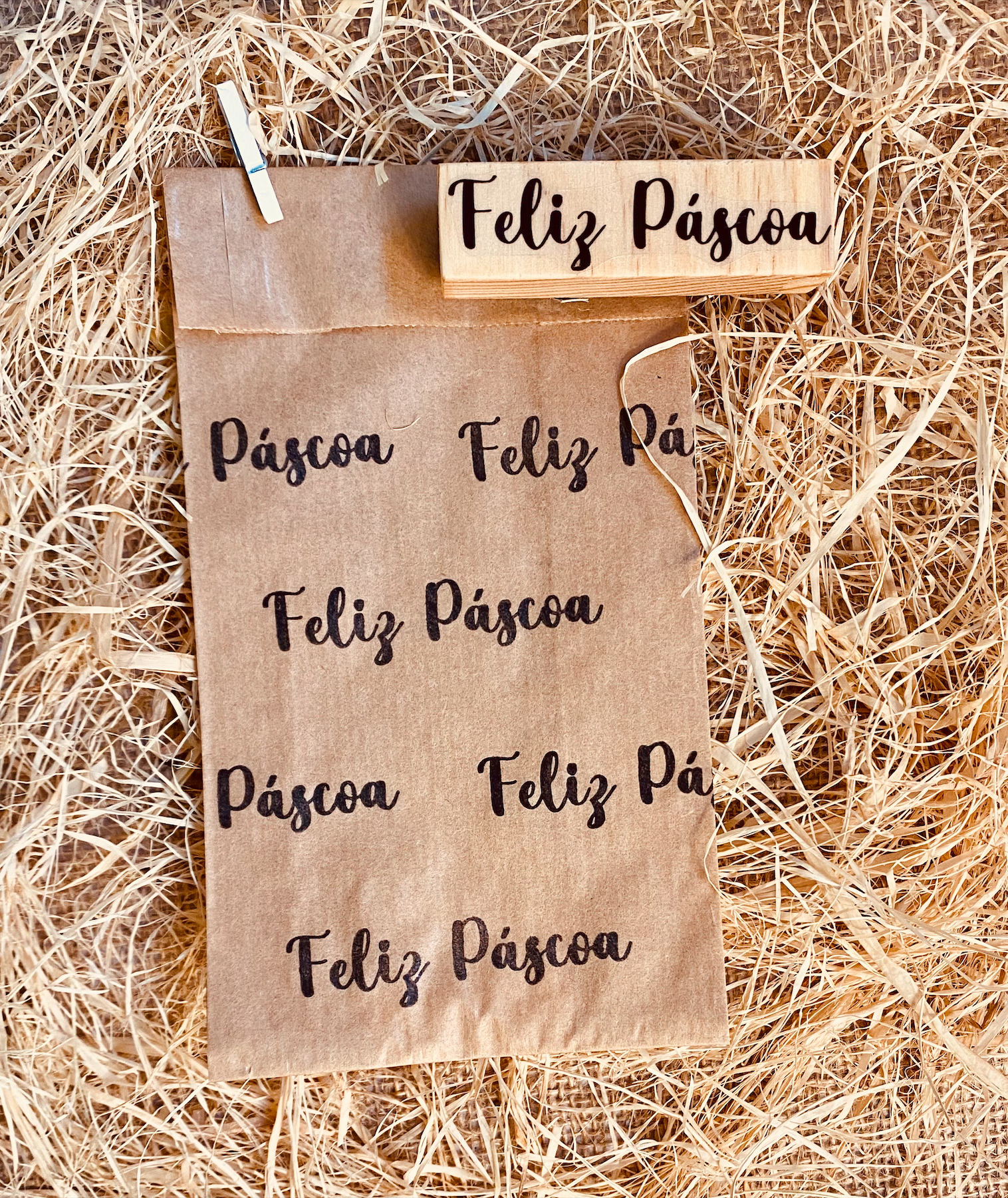 Saco de papel com a frase Feliz Páscoa em preto e carimbo de madeira
