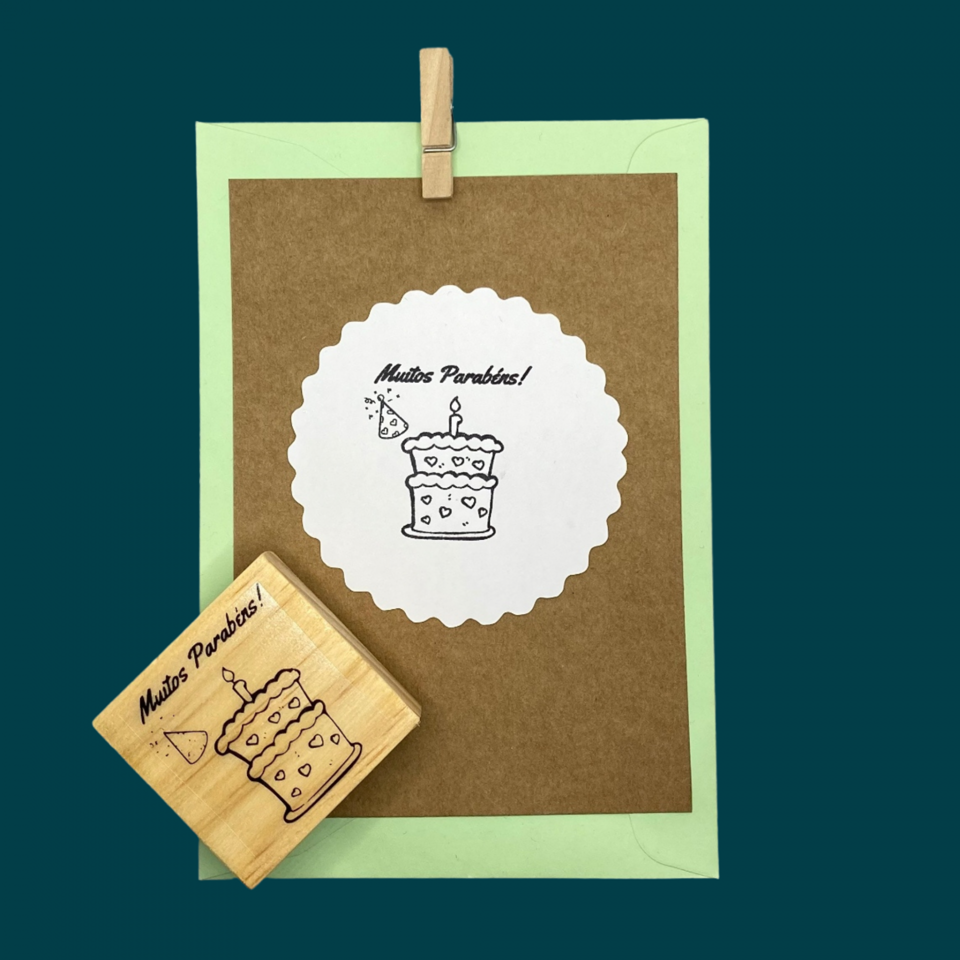 Cartão castanho com etiqueta branca e carimbo de madeira com desenho de bolo de aniversário