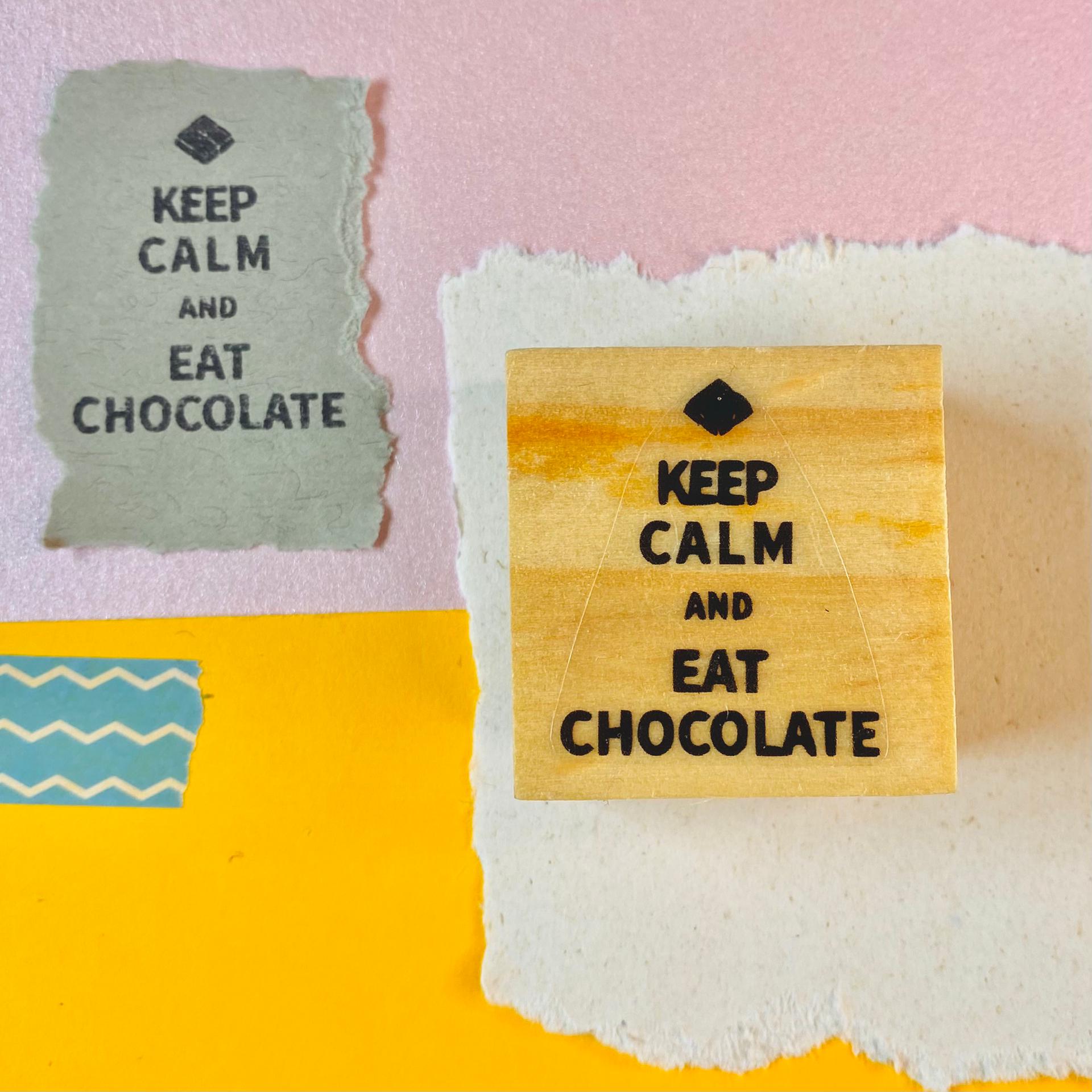 Selo de borracha 'Keep Calm and Eat Chocolate' com materiais de papel colorido ao redor