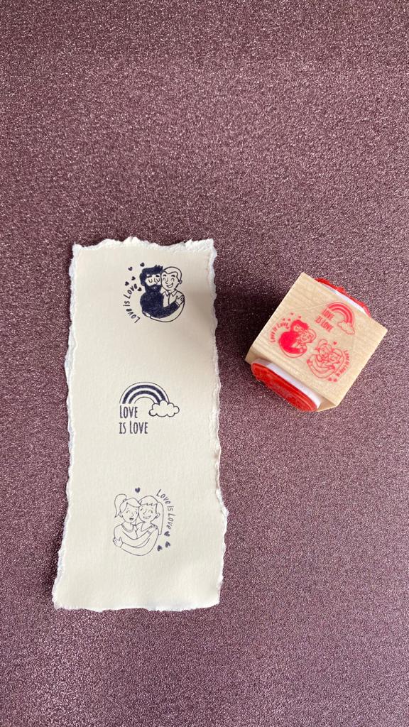 Carimbo de madeira quadrado com estampas em papel mostrando frases e desenhos relacionados a amor