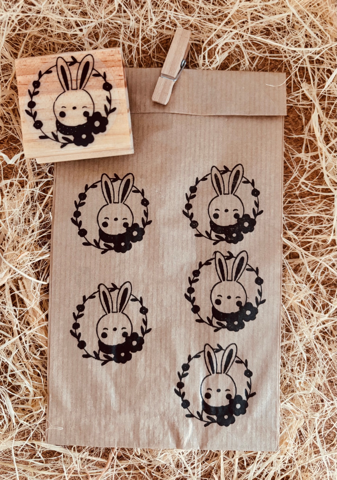 Saco de papel com carimbo de coelho estampado e carimbo de madeira ao lado