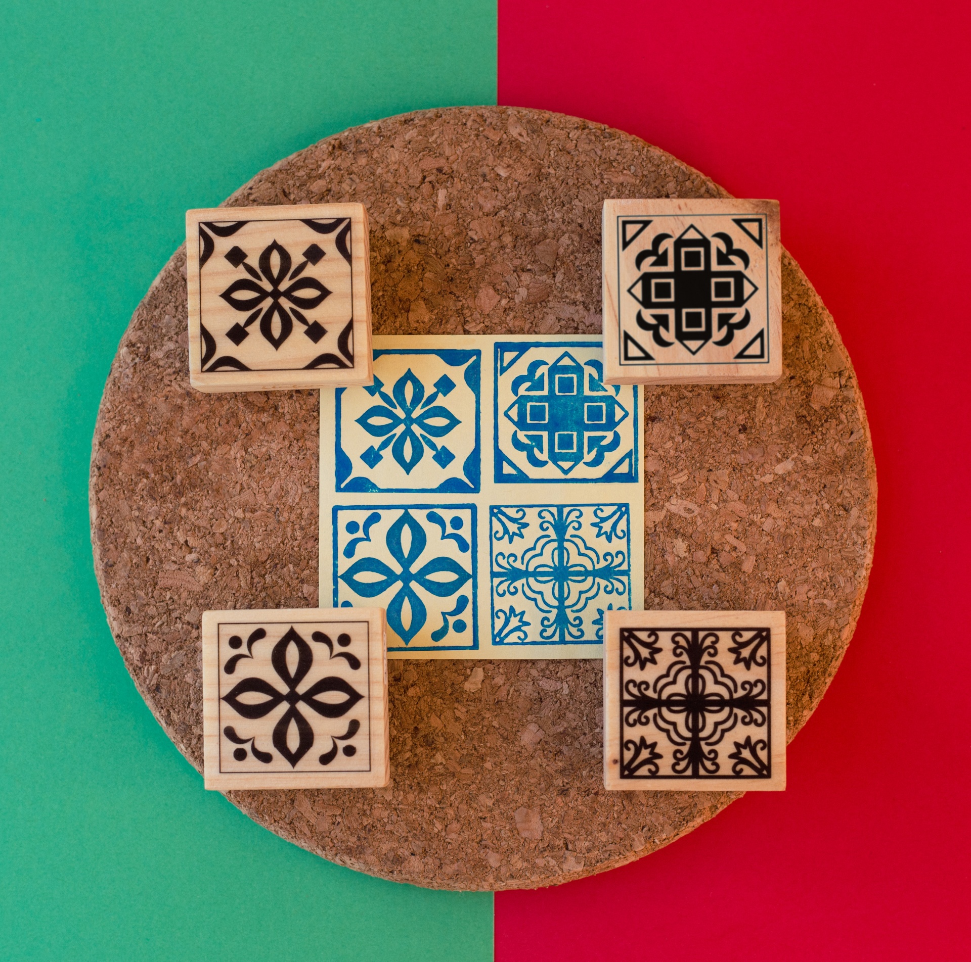 Carimbos de madeira com padrões geométricos sobre base de cortiça e azulejos azuis e brancos