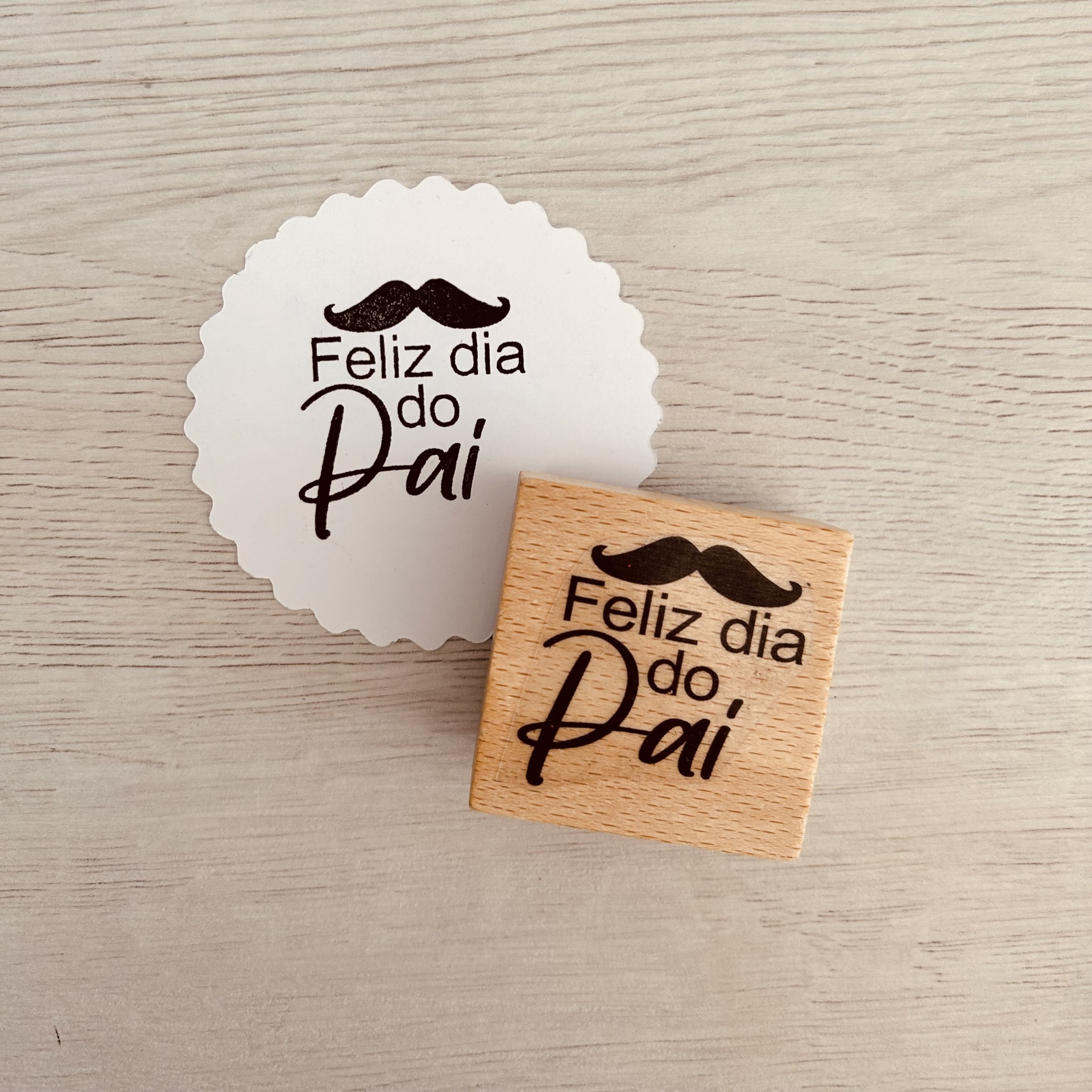Carimbo de madeira com frase Feliz dia do Pai e impressão circular com o mesmo texto e desenho.
