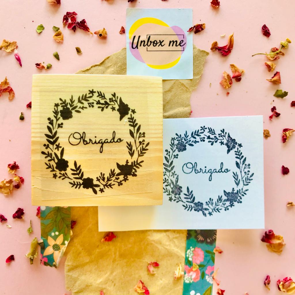 Selo de madeira com desenho floral e palavra Obrigado, cartão e fundo decorativo