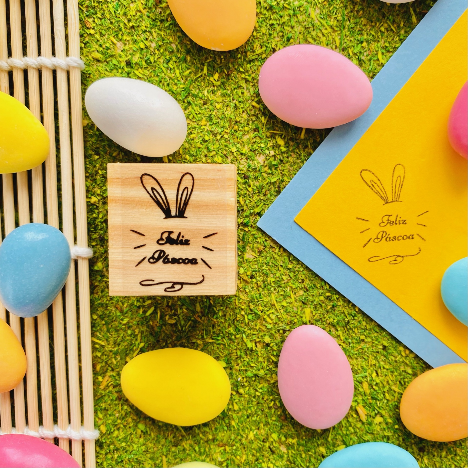 Carimbos de madeira com desenho de coelho e ovos coloridos sobre relva artificial