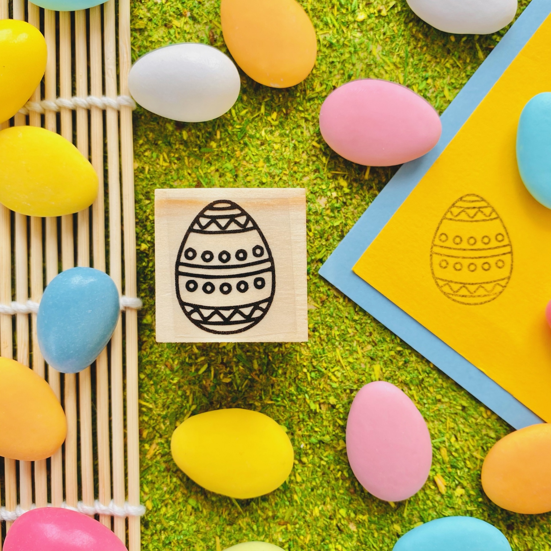 Carimbo de ovo de Páscoa decorado e ovos coloridos sobre superfície verde