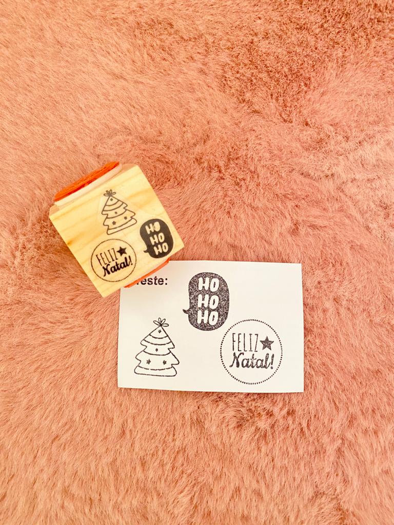 Carimbo de madeira com padrão Natal e cartão com mesmas estampas sobre tecido rosa claro