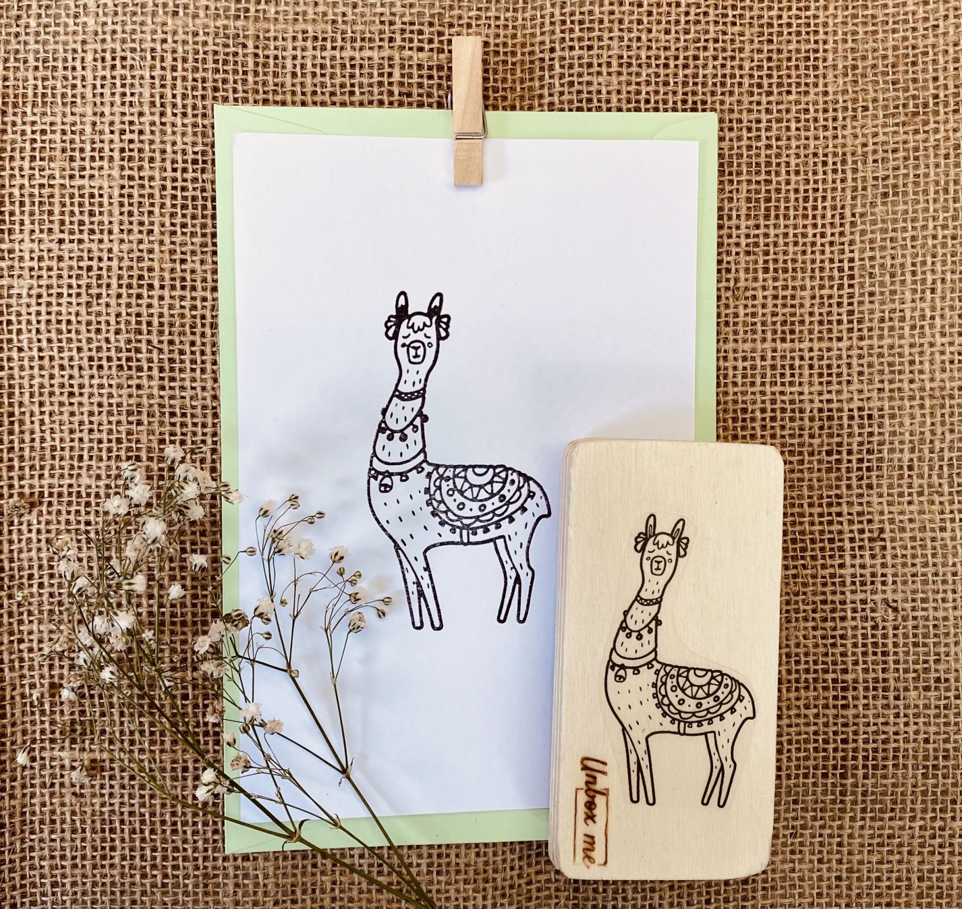 Carimbo de madeira com desenho de lhama e folha com o mesmo desenho sobre tecido rústico