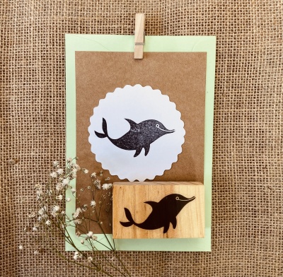 Carimbo de golfinho preto em madeira com cartão e pregador sobre tecido rústico