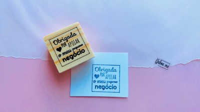 Carimbo de madeira com almofada amarela e papel azul com carimbo sobre fundo azul e rosa