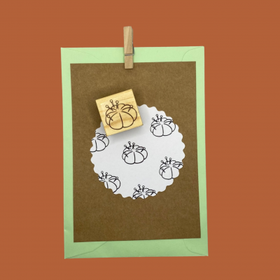 Carimbo de madeira com desenho de almofada de alfinetes sobre etiquetas e envelope coloridos