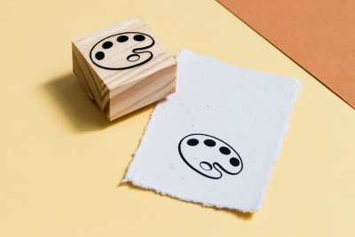 Carimbo de paleta de pintor com papel branco na superfície amarela