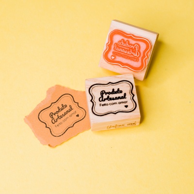 Dois carimbos de madeira para artesanato e papel com carimbo aplicado sobre fundo amarelo