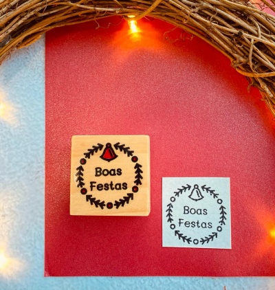 Carimbo de madeira e impressão com desenho natalício e texto Boas Festas