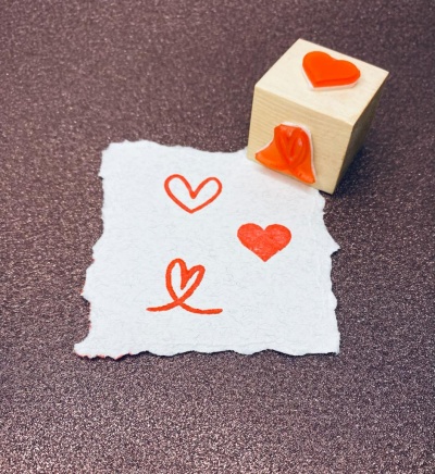 Carimbo de madeira com símbolo de coração e papel com corações estampados