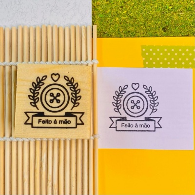 Etiqueta de madeira com design 'Feito à mão' ao lado de impressão semelhante em papel