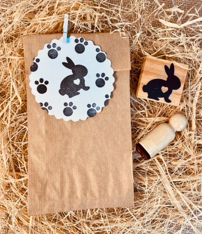 Saco de papel com etiqueta e carimbos de coelho sobre palha