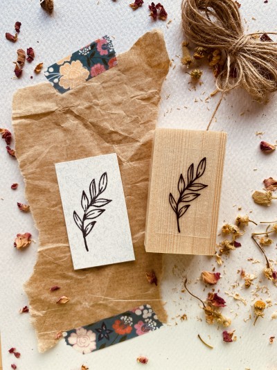 Carimbo de madeira com estampa de folhas em papel kraft e papel branco com flores secas e corda de sisal