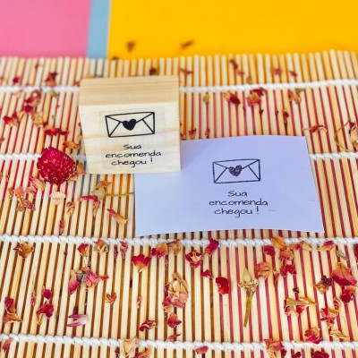 Carimbo e papel com a frase Sua encomenda chegou com envelope e coração sobre bambu com pétalas de flores