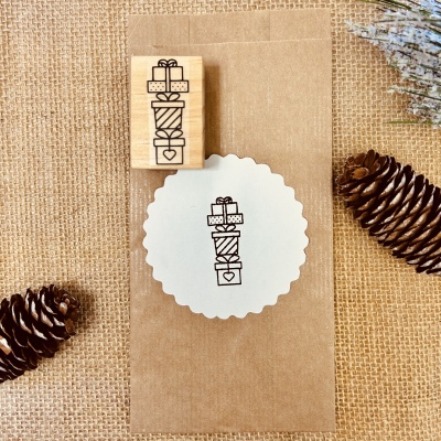 Carimbo de madeira com desenho de presentes e saco em fundo de juta.