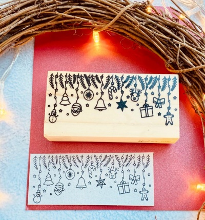 Carimbo de madeira com motivos de Natal pendurados em ramos de árvore.