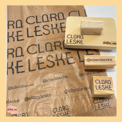 Carimbos de madeira e saco de papel com textos Clara Leske e @claraleske