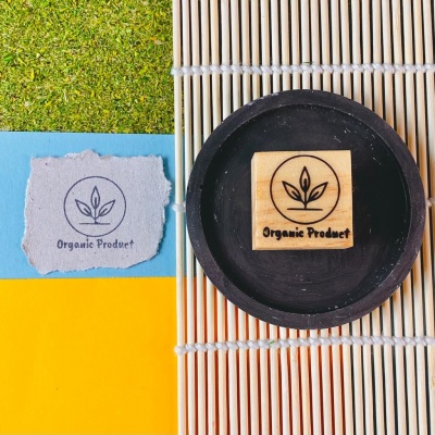 Carimbo de madeira com design orgânico em prato preto sobre tapete de bambu e papel colorido