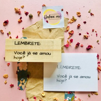 Notas com lembrete em madeira e papel, fundo rosa com pétalas secas e papel kraft