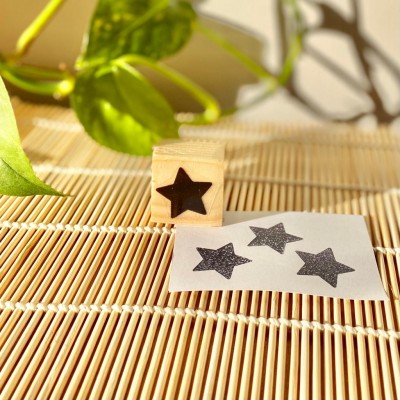 Bloco de carimbo em madeira com estrela preta e papel com estrelas carimbadas
