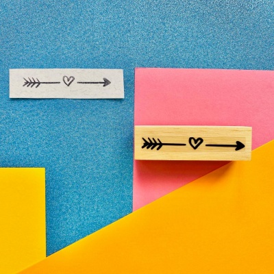 Carimbo de madeira com design de flecha e coração e impressão em papel colorido