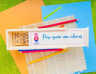 Estojo de madeira com carimbos e lápis coloridos sobre fundo colorido